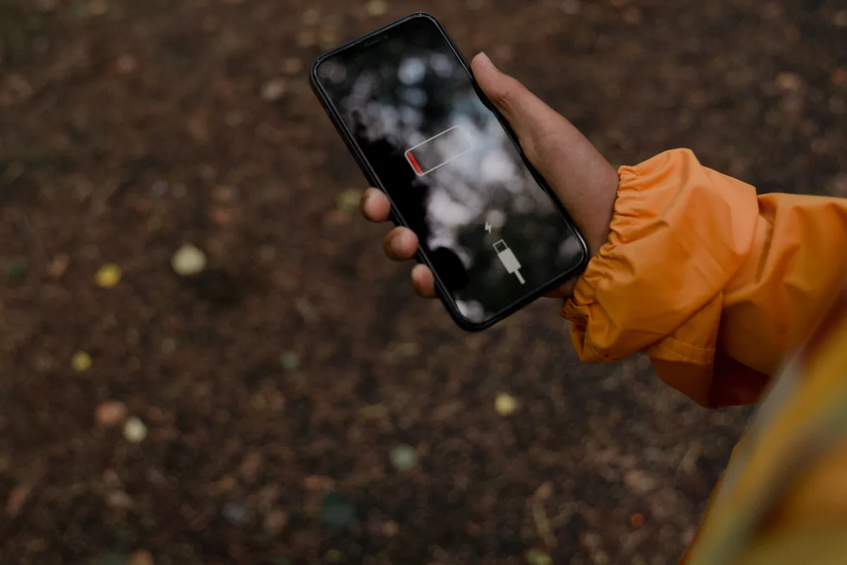 Leeres Batteriesymbol auf einem dunklen Smartphone-Display, im Freien gehalten