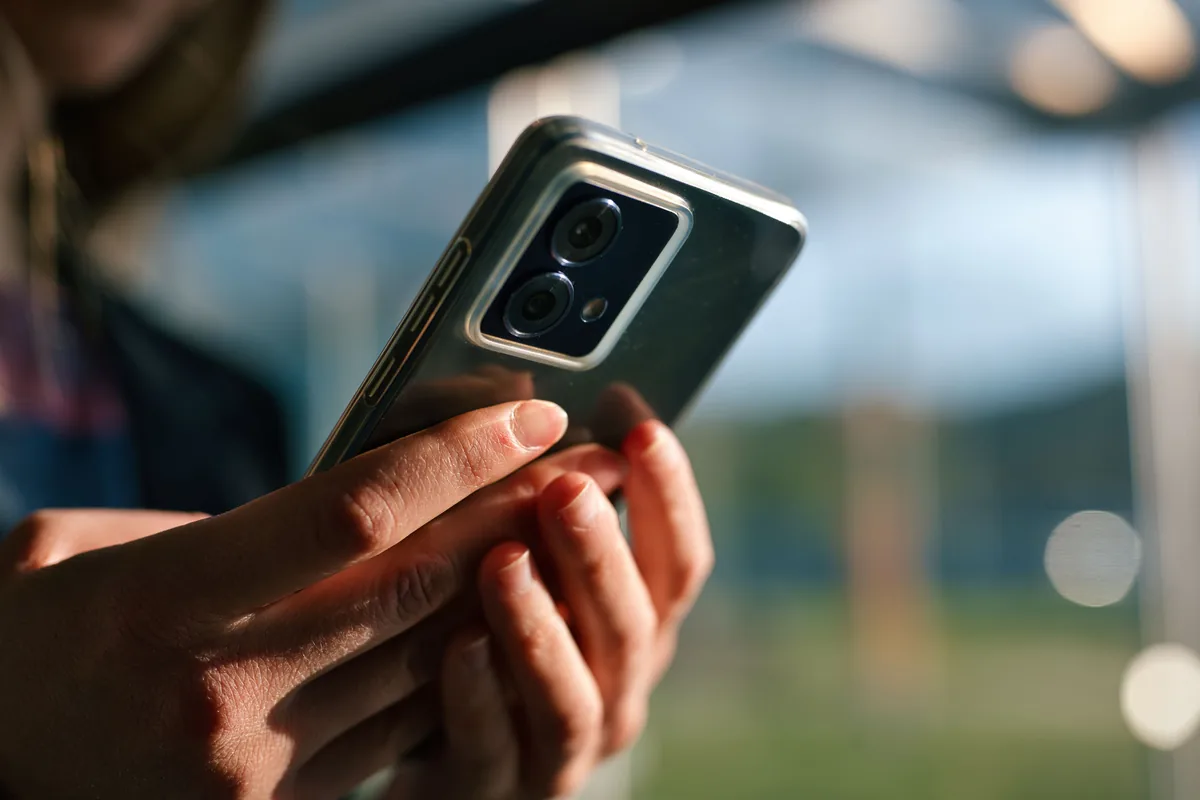 H&auml;nde halten im Freien ein Smartphone, unscharfer Hintergrund bei Tageslicht